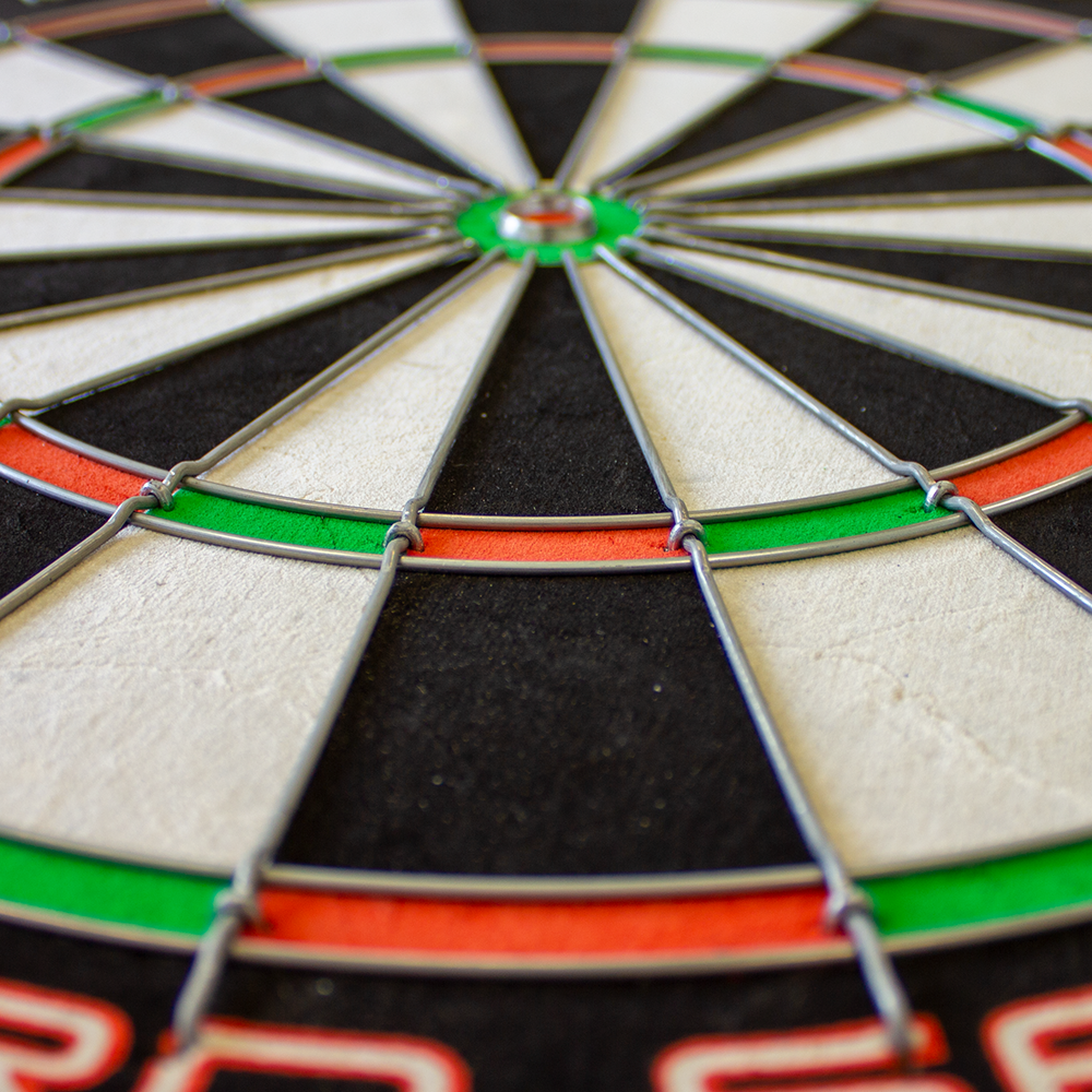 1602_Winmau_Pro_SFB_Dartboard_4 Das Bild zeigt ein Winmau Pro SFB Dartboard aus der Nähe. Die Felder sind klar in Schwarz, Weiß, Rot und Grün unterteilt und von Metalldrähten abgegrenzt.