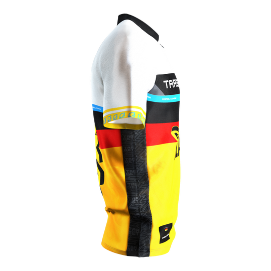 Das Bild zeigt das Target Coolplay Gabriel Clemens 2025 Dartshirt aus seitlicher Perspektive. Das Shirt ist überwiegend in Weiß, Schwarz, Rot und Gelb gehalten und trägt auffällige Designs sowie den Namen "Gabriel Clemens".