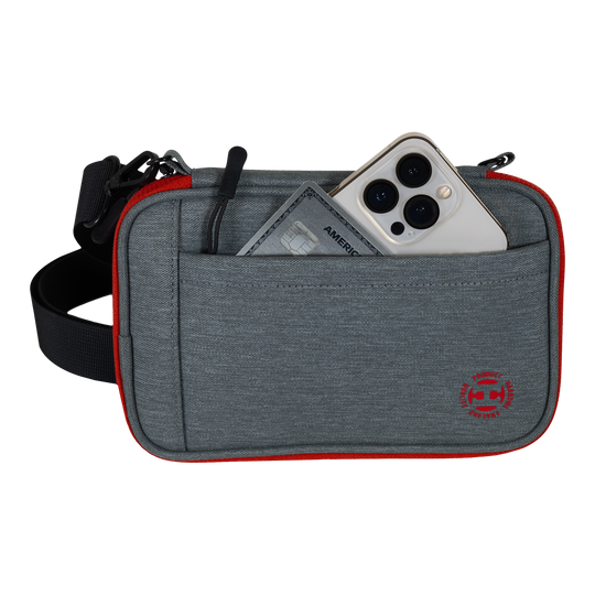 Harrows Smart Case XL dart wallet Das Bild zeigt eine graue Tasche mit rotem Rand und einem schwarzen Gurt. In der Vordertasche stecken ein Smartphone und eine Kreditkarte.