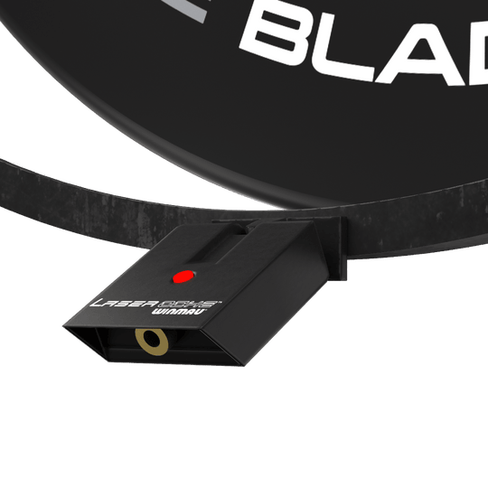 Winmau Plasma Accessory Set Das Bild zeigt das Winmau Plasma Zubehör Set, das an einem Dartboard befestigt ist. Sichtbar ist ein schwarzes Gerät mit der Aufschrift "Laser Oche Winmau" und einem roten Knopf.