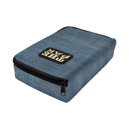 715TP_The_PAK_Jeans_Editon_Darttasche_2 Die Abbildung zeigt die "The Pak Jeans Edition Darttasche" in einem blauen Jeans-Design. Auf der Vorderseite befindet sich ein aufgenähtes Label mit der Aufschrift "THE PAK" und ein schwarzer Reißverschluss.