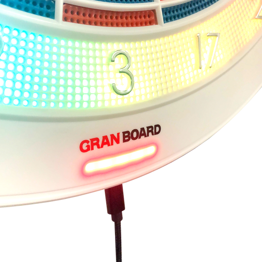 g01440_GranBoard_132_Elektronisches_Dartboard_4 Das Bild zeigt einen Ausschnitt des elektronischen Dartboards "GranBoard 132" mit leuchtenden LED-Lichtern um die Zahlenbereiche. Darunter ist das Logo "Gran Board" in roten und schwarzen Buchstaben zu sehen.