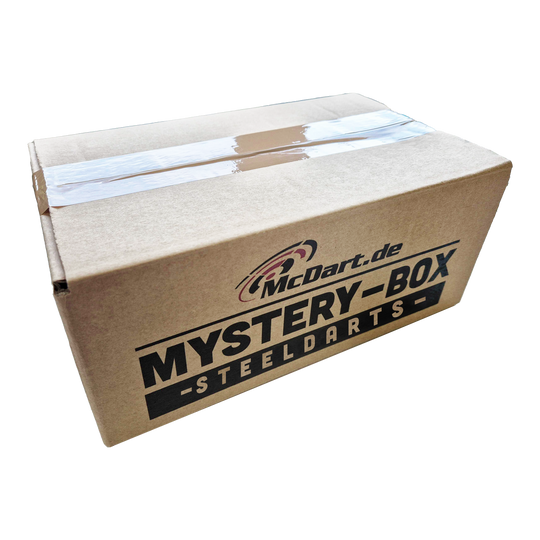 Phil Taylor Mystery Soft Dart Fan Box Auf dem Bild ist ein Karton mit der Aufschrift "McDart.de Mystery-Box Steeldarts" zu sehen. Die Box ist mit durchsichtigem Klebeband verschlossen.